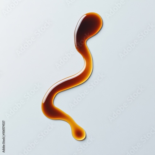 A single, thin stream of brown sauce drizzled on a white background.