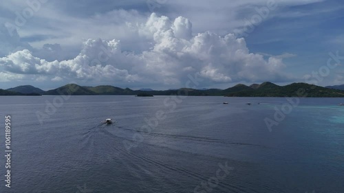 Stunning Drone View of a Boat in Bay Leading to a Secluded Beach and Turquoise Lagoon with White Sand, Boats, and Green Mountains in the Philippines