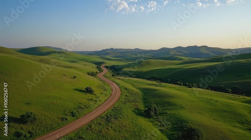 Curvy road through expansive green countryside, aerial shot showcasing natural beauty, quiet atmosphere