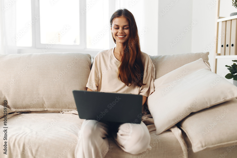 Smiling woman typing on laptop in cozy living room, enjoying technology and freelance job Smiling woman typing on laptop in cozy living room, enjoying technology and freelance job