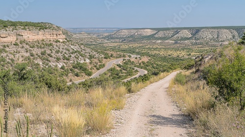 Scenic view of a winding dirt road through a lush valley and rolling hills.