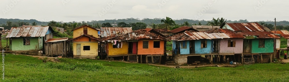Colorful houses on stilts in a rural setting with a lush green landscape.