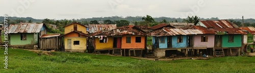 Colorful houses on stilts in a rural setting with a lush green landscape.