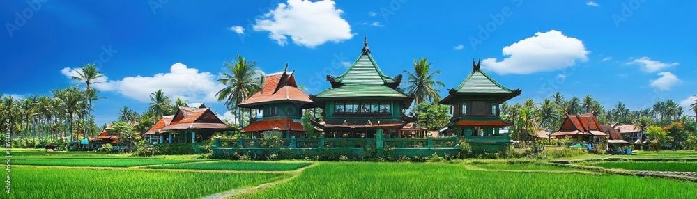 A picturesque landscape featuring traditional architecture amidst lush green rice fields. A picturesque landscape featuring traditional architecture amidst lush green rice fields.