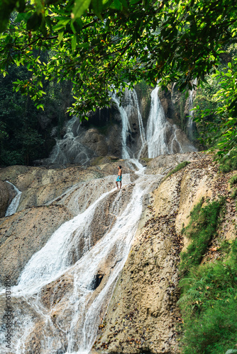 Hiker standing in front of huge Jungle waterfall surrounded by lush jungle vegetation