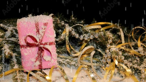 Christmas background with a green fir tree, a gift and sweets on a black background in the video it is snowing