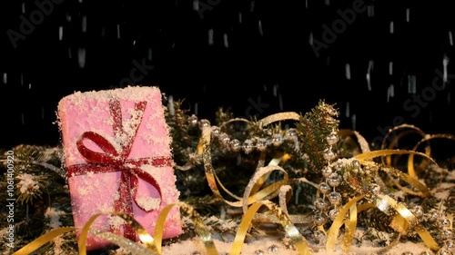 Christmas background with a green fir tree, a gift and sweets on a black background in the video it is snowing