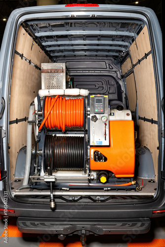 High-pressure cleaning equipment installed in van interior with hoses and cleaning tools organized for efficient work, industrial cleaning concept