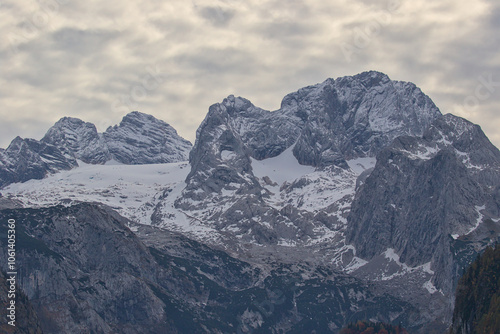 Rocky, snow-dusted mountain peaks under dense structured clouds. The uneven contours of the landscape evoke a feeling of loneliness and the majesty of nature in its rough and powerful form. Alps. photo