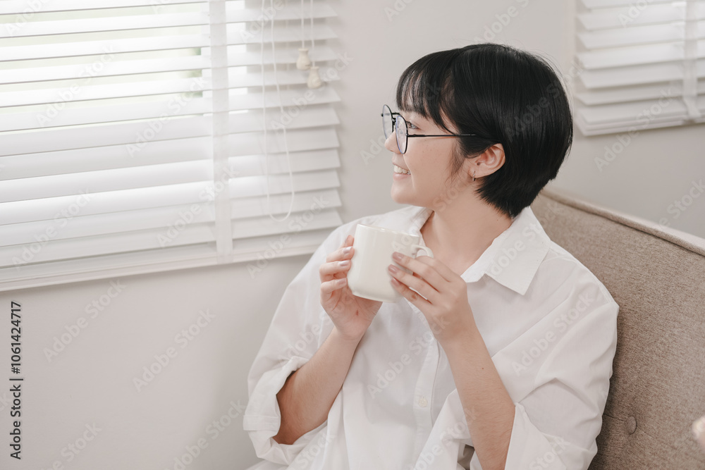Young woman enjoys warm beverage while relaxing at home in natural light Young woman enjoys warm beverage while relaxing at home in natural light