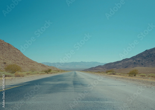 A wide-angle photograph of an empty highway in the middle of the American desert with a clear blue sky, cinematic in style, beautiful yet melancholic, minimalistic with muted tones.