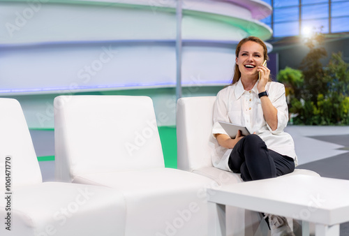 Businesswoman sitting in a business building hall, talking on the phone and laughing.