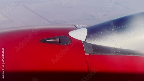 Close up of air intake of turbo engine of airplane flying above ground. Seam of docking of aeropanels of aero engine housing with rivets is detail. Red engine of aircraft and features of aerostructure