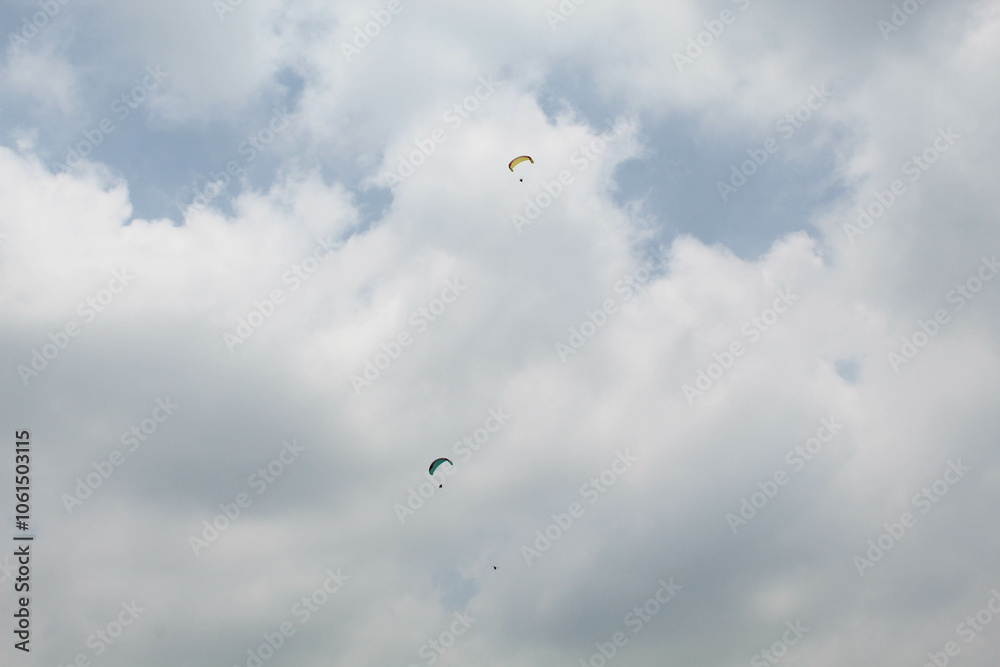 Two parachutes of paragliders with cloudy sky background Two parachutes of paragliders with cloudy sky background