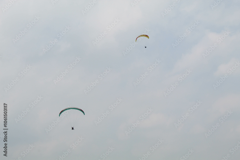 Two parachutes of paragliders with cloudy sky background Two parachutes of paragliders with cloudy sky background