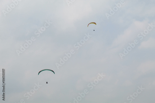 Two parachutes of paragliders with cloudy sky background photo