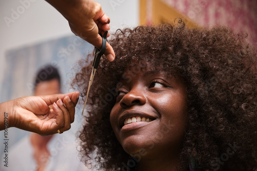 Hairdresser styling afro hair of a customer using scissors photo