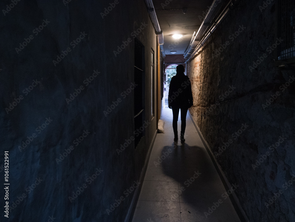 Obraz premium Silhouette of a person woman standing in a dark corridor tunnel