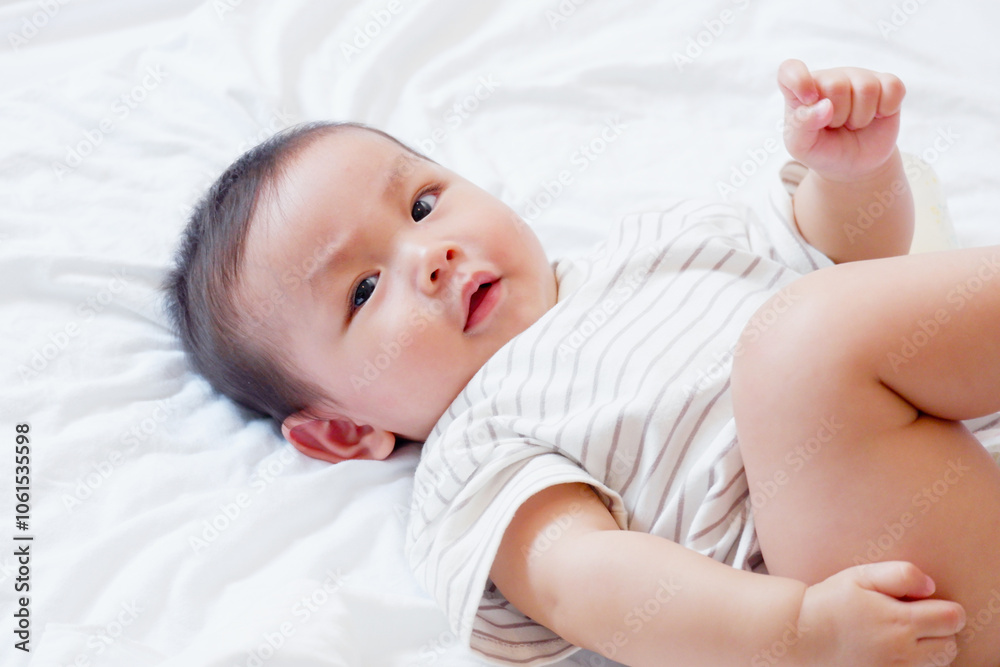 Cute little baby smiling and lying on a white bed.