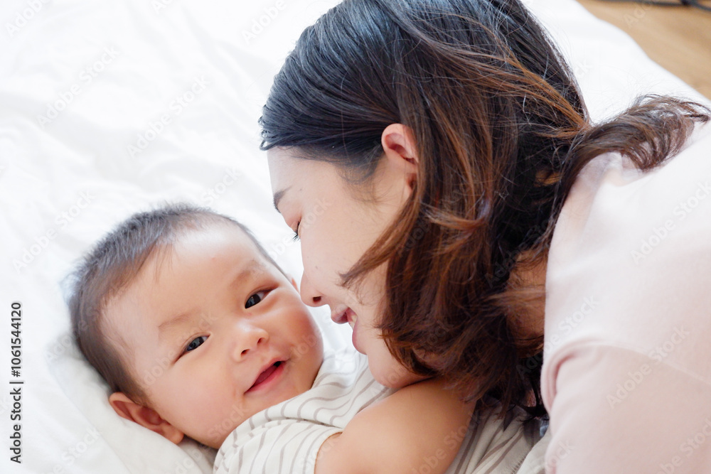 A mother and her cute little baby are lying on a white bed. A mother and her cute little baby are lying on a white bed.