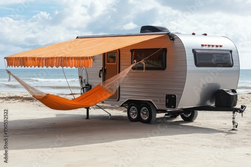 Modern Camper Trailer with Awning and Hammock on a Sandy Beach with Ocean View Under a Cloudy Sky