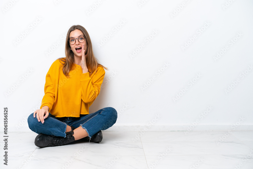 Young caucasian woman sitting on the floor isolated on white background shouting with mouth wide open Young caucasian woman sitting on the floor isolated on white background shouting with mouth wide open