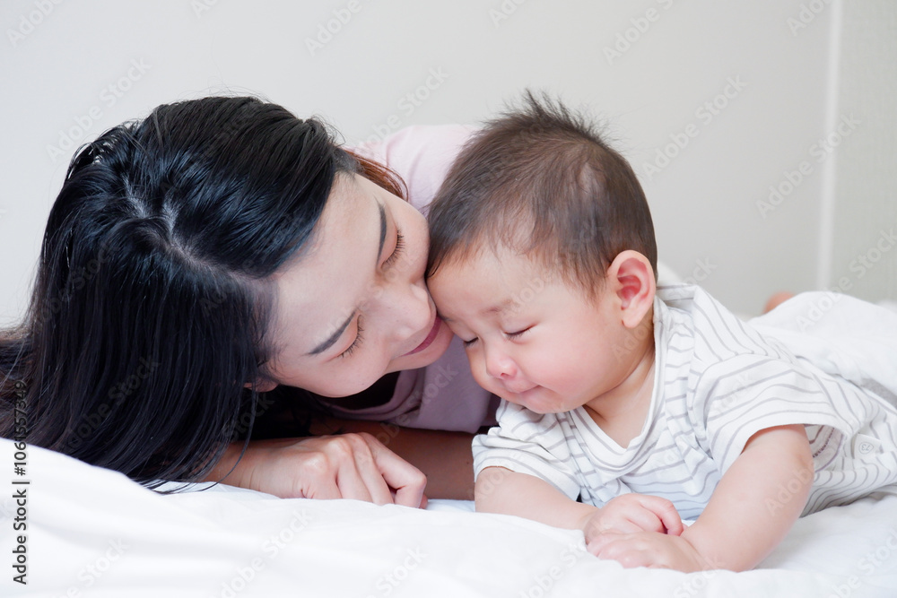 A mother and her cute little baby are lying on a white bed. A mother and her cute little baby are lying on a white bed.