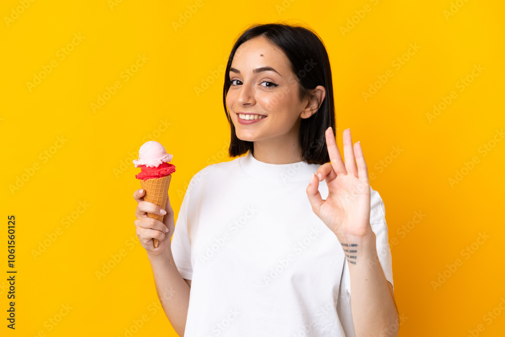 Young caucasian woman with a cornet ice cream isolated on yellow background showing ok sign with fingers Young caucasian woman with a cornet ice cream isolated on yellow background showing ok sign with fingers