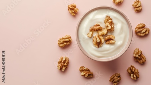A pink bowl of yogurt topped with walnuts on a pink background.