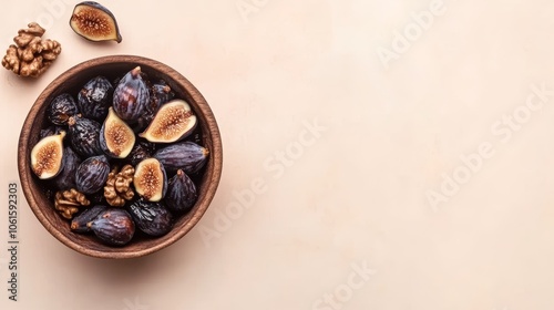 Bowl of fresh figs and walnuts on a light pink background.