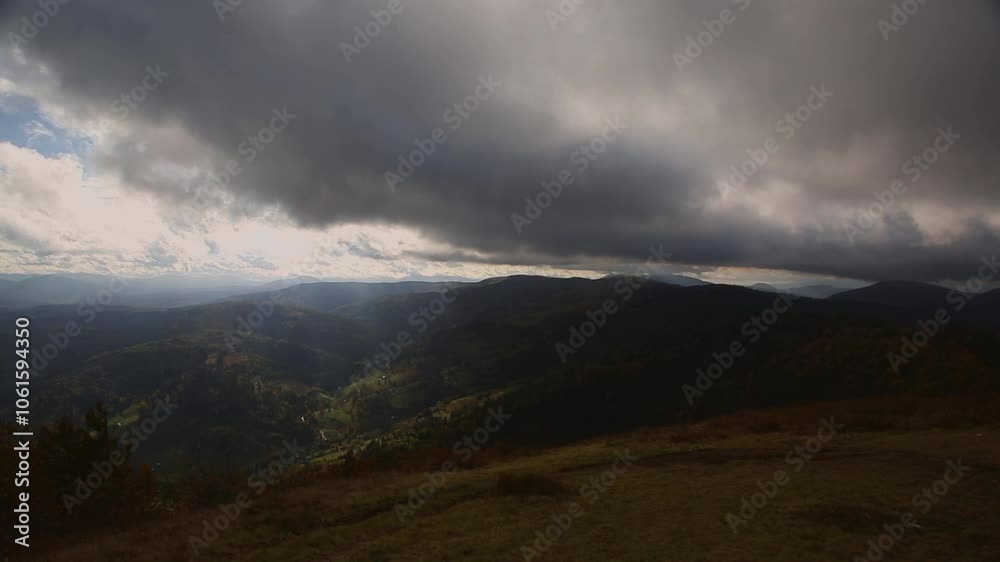 The sun's rays shine through storm clouds that fly over the tops of high mountains. The sun's rays shine through storm clouds that fly over the tops of high mountains.