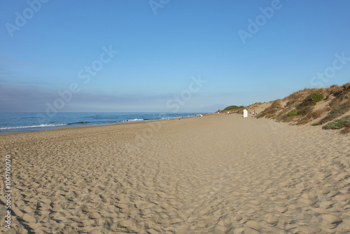 Lonely Cabopino beach, with waves reaching the sandy shore, horizon line and clear sky. In Artola Dunes, Marbella, Malaga, Andalusia, Spain, Europe