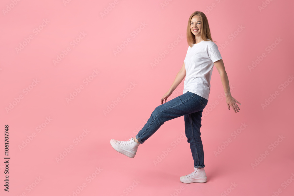 A cheerful young woman striking a playful pose on a soft pink backdrop with copy space A cheerful young woman striking a playful pose on a soft pink backdrop with copy space
