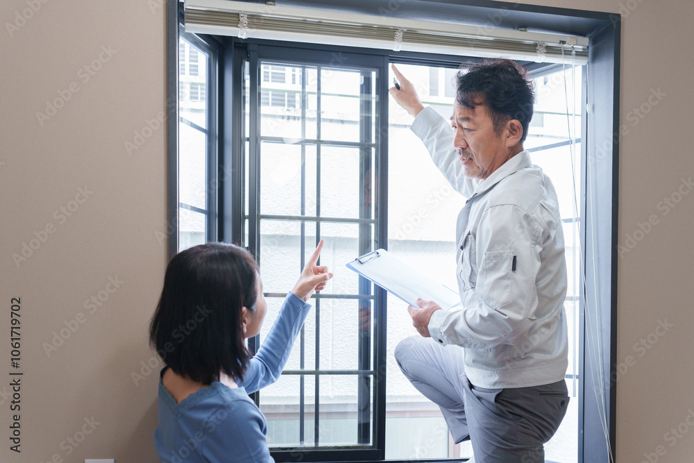Obraz premium 窓のサッシの点検をする修理業者と客
