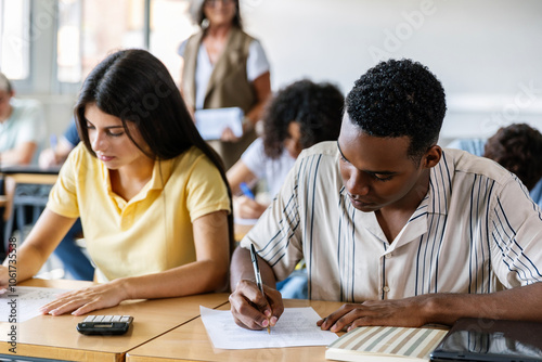 Young multiracial students doing an exam at high school. African boy and caucasian girl doing exercises in classroom. Education lifestyle and back to school concept. photo