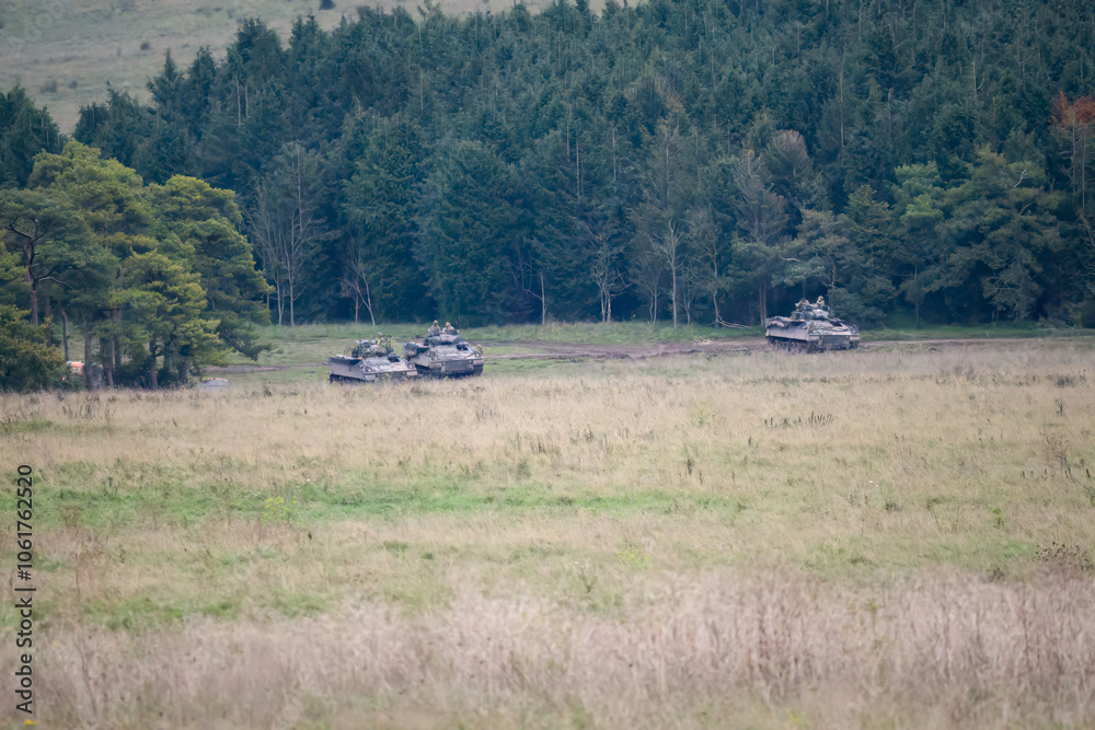 Fototapeta premium a group of a British army Warrior FV510 light infantry fighting vehicle tanks in action on a military exercise, Wiltshire UK