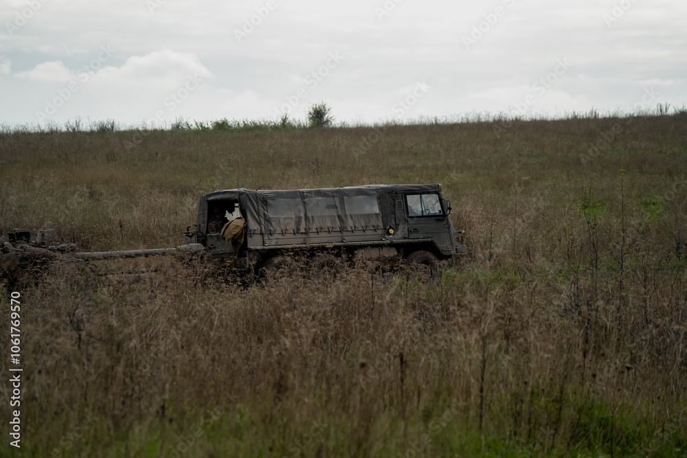 Fototapeta premium British army bae systems, Puch, Daimler, Pinzgauer High-Mobility All-Terrain 6x6 vehicle towing a 105mm Light Artillery Gun on a military exercise