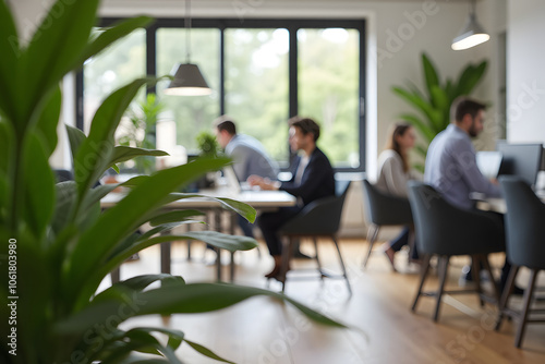 Modern open plan office with focused professionals and greenery, greenery in focus, background blurred