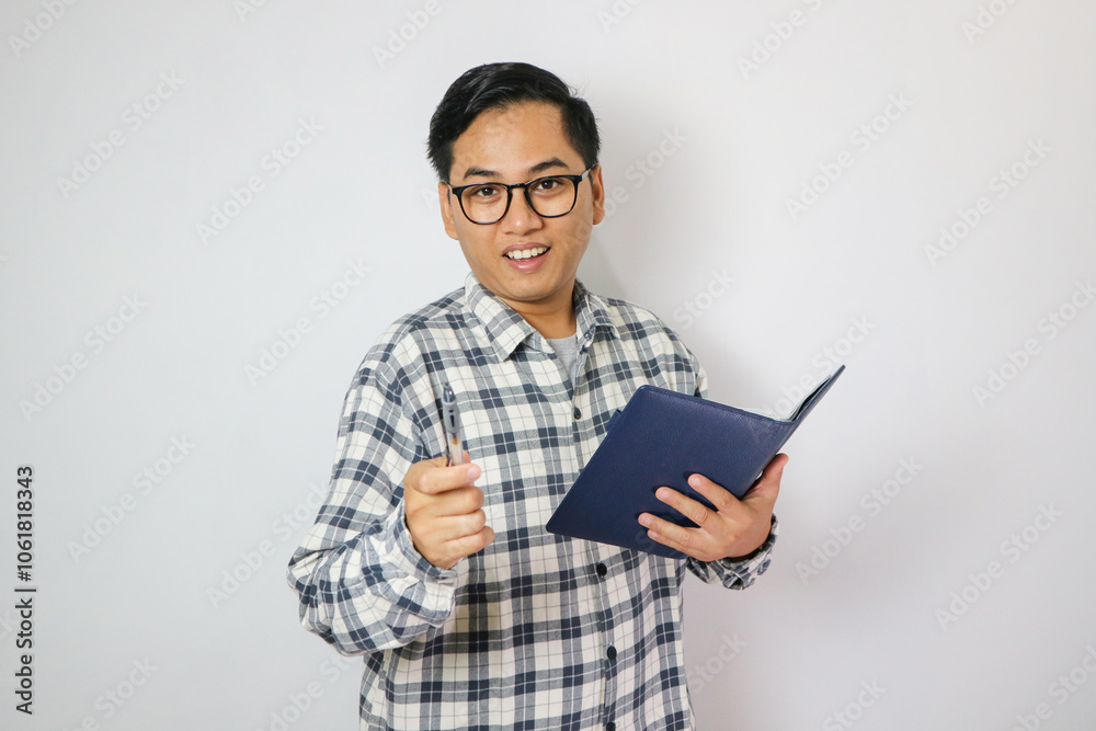 Portrait young man wear glasses casual shirt holding the books happy smile point finger at you isolated. Portrait young man wear glasses casual shirt holding the books happy smile point finger at you isolated.