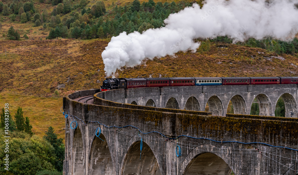 Naklejka premium Steam train at Glenfinnan Autumn in Scotland with reflections in the lochs