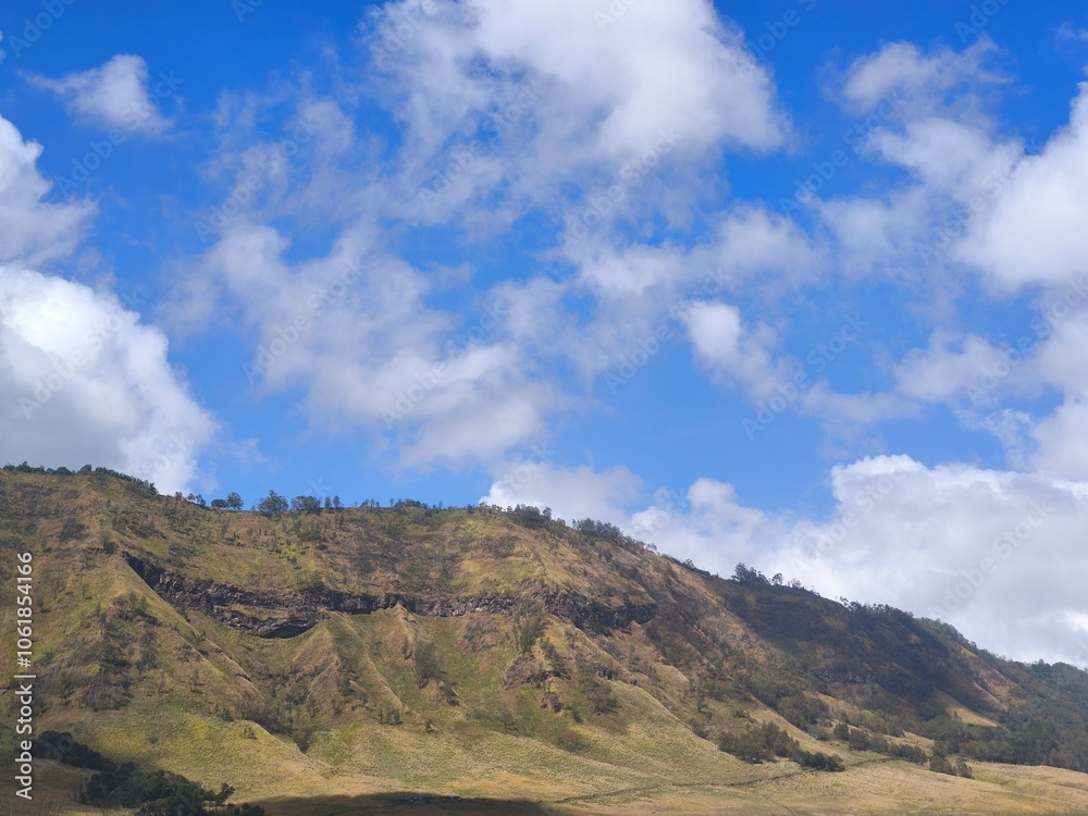 Landscape of rolling hills with vibrant green grass under a blue sky