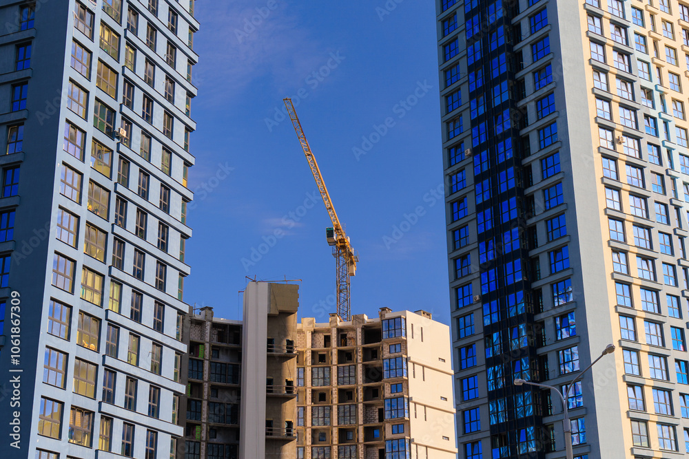 Fototapeta premium Construction cranes and new buildings, construction work of modern skyscrapers on a sunny day.