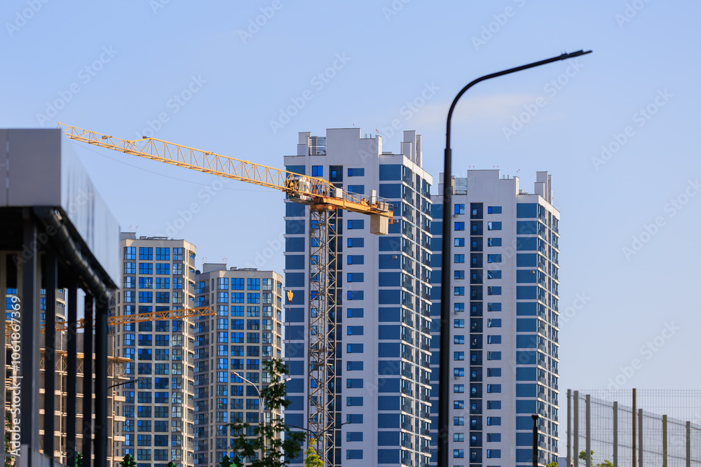 Fototapeta premium Construction cranes and new buildings, construction work of modern skyscrapers on a sunny day.