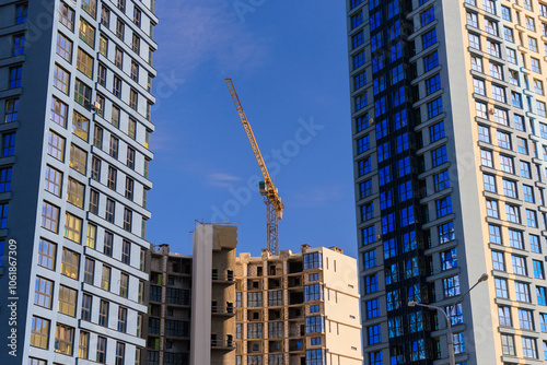 Construction cranes and new buildings, construction work of modern skyscrapers on a sunny day.