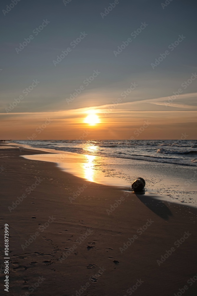 Sandy beach with the sun in the background. Beautiful sunset over the Baltic Sea in Gdynia, Poland.