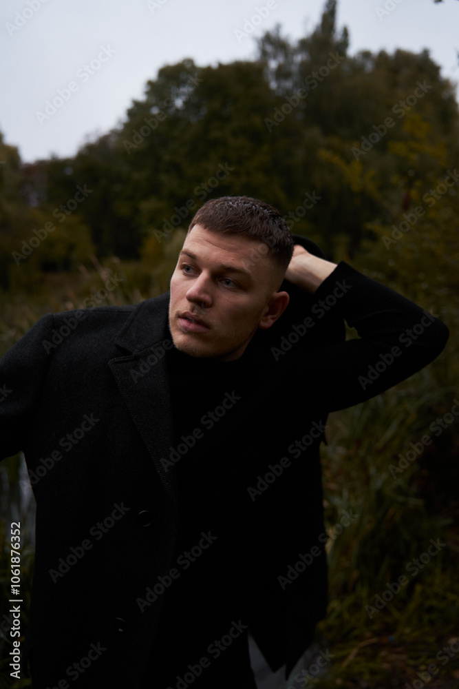 A European man in a black coat walks in the park at dusk in autumn A European man in a black coat walks in the park at dusk in autumn