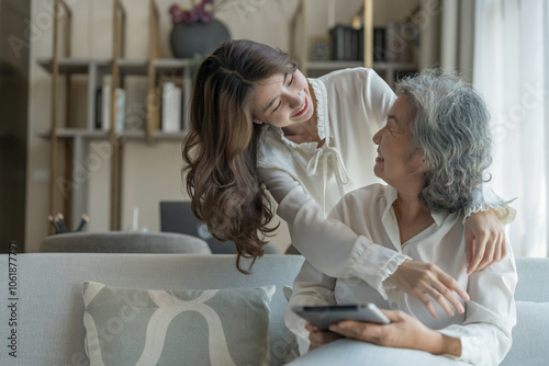 portrait of bonding senior mother and adult daughter,old woman sitting on couch,a young female standing behind and embracing her mom in living room,hugging with love, smile,affection