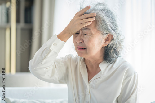 portrait a stressful senior woman suffering with headache alone at home,elderly,health care and medical,health insurance