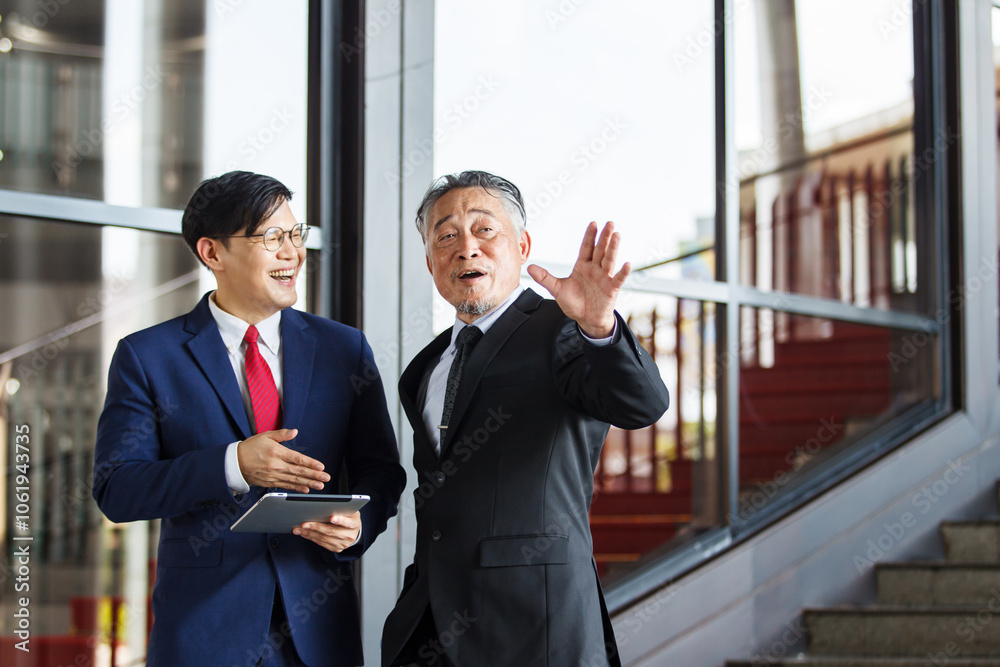 Two Asian businesspeople having a business discussion in the office building. Two Asian businesspeople having a business discussion in the office building.