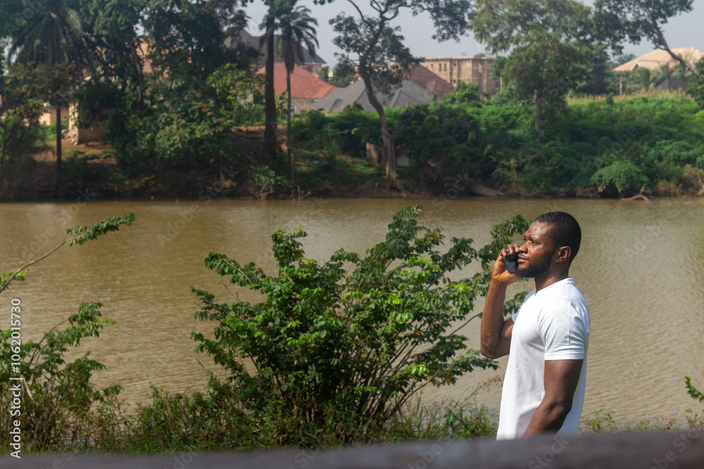 Man by rhe river bank talking on the phone Man by rhe river bank talking on the phone